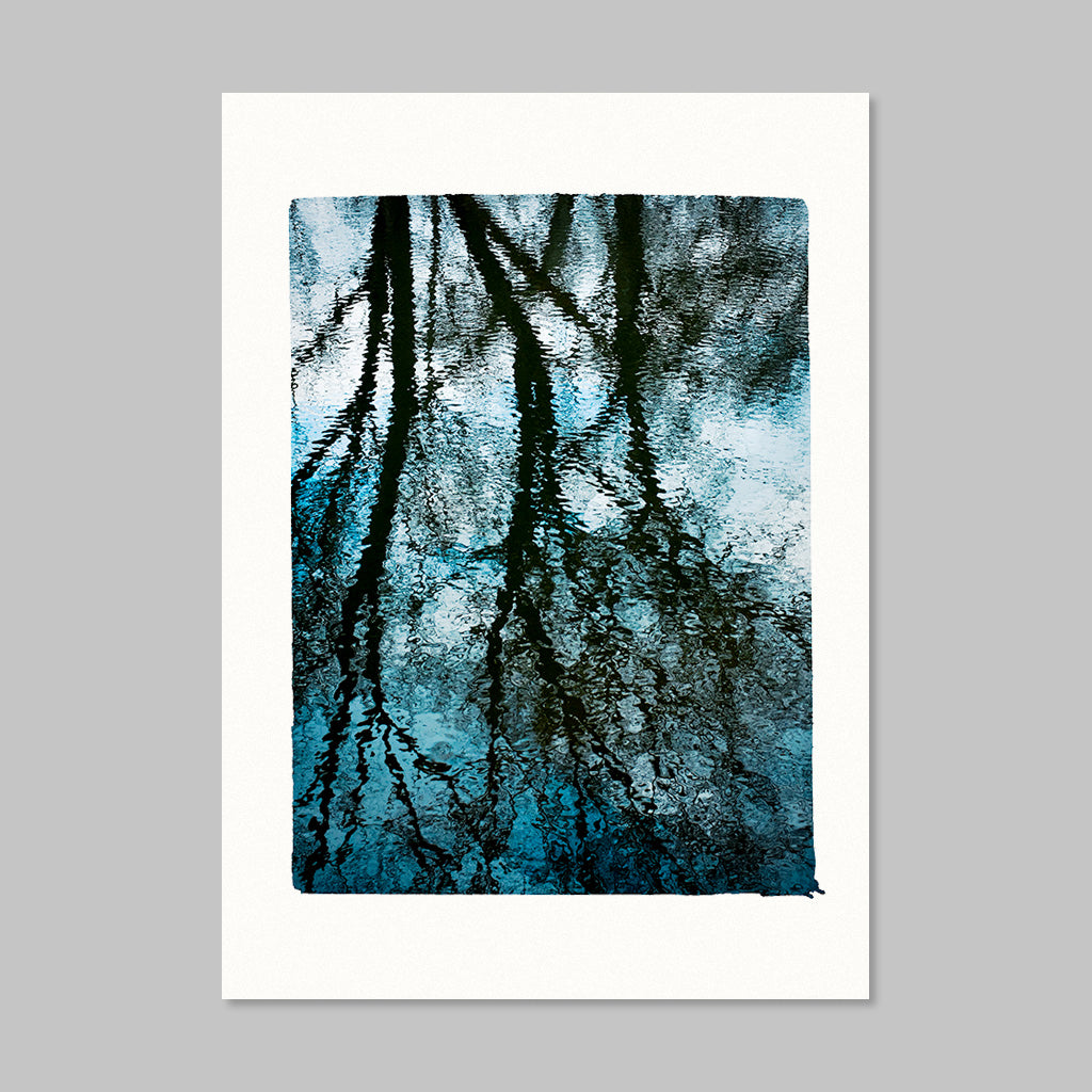 A vertical art print featuring an abstract tree branch pattern in deep blue, teal, and black, presented with a wide white border on a neutral gray background.