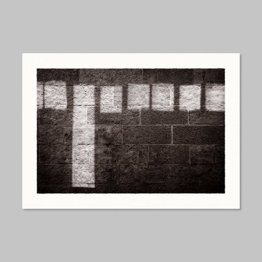 Monochrome photo of sunlight reflections on a stone wall.